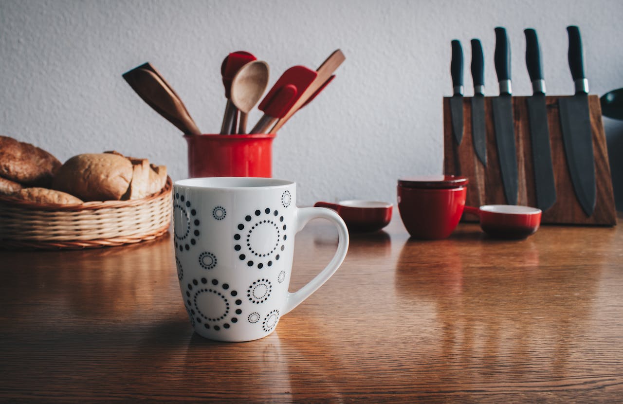 home-services-02 A cozy kitchen scene featuring a decorative mug, cutlery set, and fresh bread basket on a wooden table.